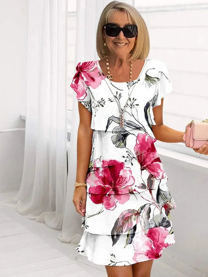 Woman wearing a floral dress with pink flowers in a bright room.